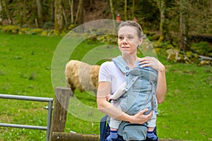 Happy woman looking to distance while holding and carrying it in a baby carrier photo