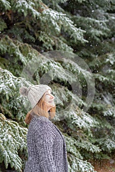 Happy woman looking up at snow falling