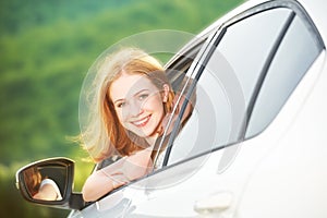 Happy woman looks out the car window on nature