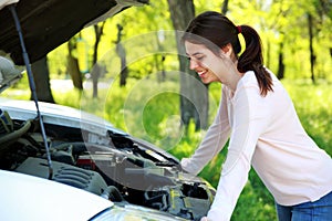 Happy woman looks under hood car