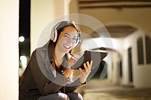 Happy woman looks at you listening tablet content