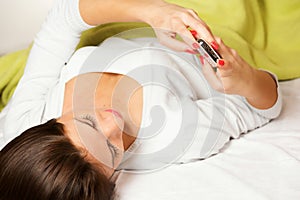 Happy woman lying on bed smiling, reading a text message