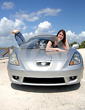 Happy woman lying on car hood