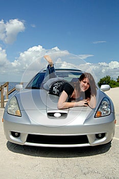 Happy woman lying on car hood