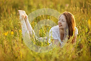 Happy woman lying in a field of grass and flowers