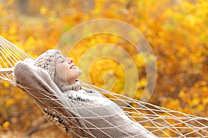 Happy woman lying on a hammock in fall season