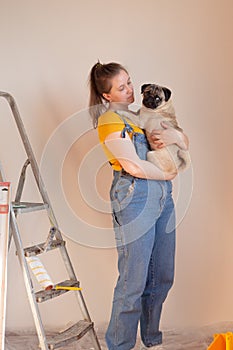 Happy woman makes repairs in her apartment with her funny pug dog. happiness in anticipation of a new home and moving