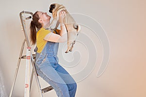 Happy woman makes repairs in her apartment with her funny pug dog. happiness in anticipation of a new home and moving