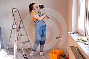 Happy woman makes repairs in her apartment with her funny pug dog. happiness in anticipation of a new home and moving