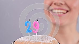 The happy woman makes a wish and blows out the candles on the 25th birthday cake. Girl celebrating birthday. Slow motion