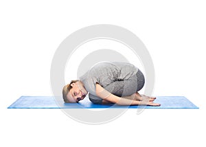 Happy woman making yoga in child pose on mat