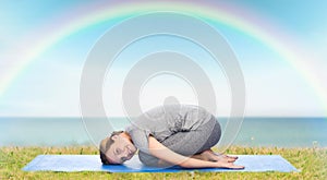 Happy woman making yoga in child pose on mat