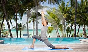 Happy woman making yoga in low lunge over beach