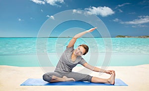 Happy woman making yoga and stretching on beach