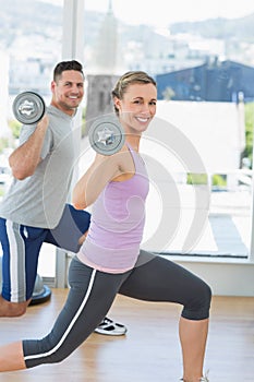 Happy woman and man exercising with barbells