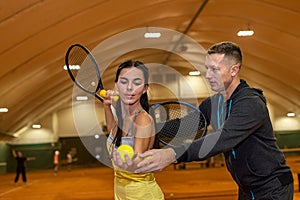 happy woman and man preparing for a doubles game of tennis on an indoor court.