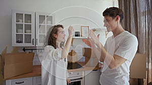 Happy woman and man show key to new apartment at camera