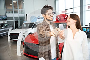 Happy woman and man showing automobile keys celebrating buying new car