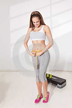 Happy woman measuring her waistline