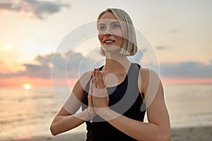 happy woman meditating on beach over sunset