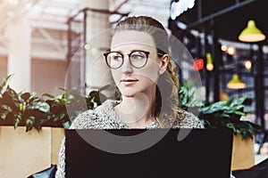 Happy woman millennial using laptop while sitting at cafe.Young businesswoman sitting in coffee shop,working on computer