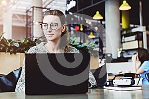 Happy woman millennial using laptop while sitting at cafe.Young businesswoman sitting in coffee shop,working on computer