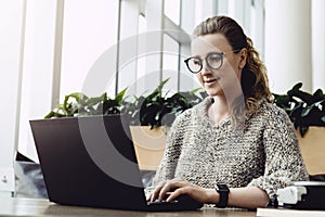 Happy woman millennial using laptop while sitting at cafe.Young businesswoman sitting in coffee shop,working on computer