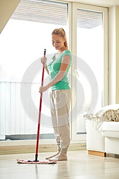 Happy woman with mop cleaning floor at home