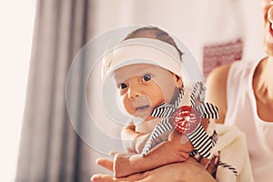 Happy woman mother holding a newborn cute baby girl in her arms at home. Mom with a child in her hands