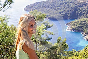 Happy woman on a mountain overlooking the sea and islands in the distance on a sunny day