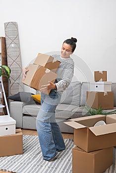 happy woman, moving into new home living room with pile of moving boxes, welcoming belonging