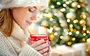 Happy woman with a mug of tea near Christmas tree