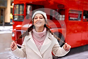 Happy woman near London double decker red old bus in winter, enjoy snow. Christmas mood holiday