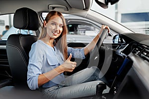 Happy woman new car owner sitting in driver seat