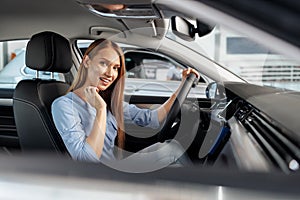 Happy woman new car owner sitting in driver seat