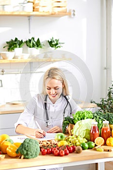 happy woman nutritionist standing near table full of healthy products in office