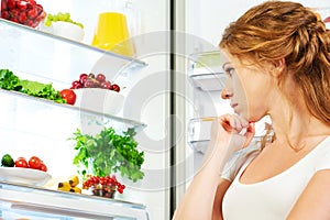 Happy woman and open refrigerator with fruits, vegetables and he