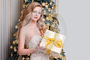 Happy woman opening gift box. Luxury blonde with Christmas gift. Merry Christmas and Happy New Year celebration theme. Young surpr