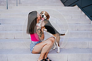 Happy woman outdoors kissing her beagle dog. Family and lifestyle concept