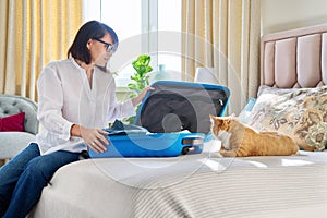 Happy woman packing suitcase with pet cat
