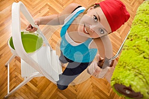 Happy woman painting the ceiling on a ladder