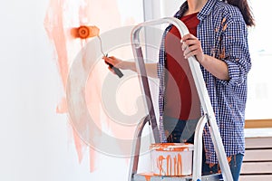 Happy smiling woman painting interior wall of new house. Redecoration, renovation, apartment repair and refreshment photo