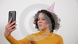 Happy woman in party hat greets talking online video call smartphone, birthday