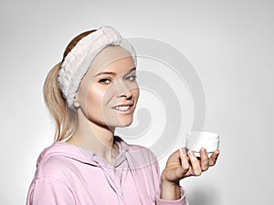 Happy woman with perfect skin applying cream on cleansed face. Concept of skincare, beauty industry and facial treatment photo