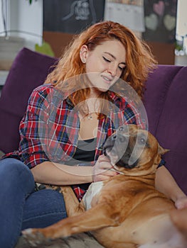 Happy woman petting her merican staffordshire terrier on couch at home in living room