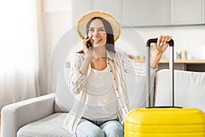 Happy woman phoning with travel luggage at home