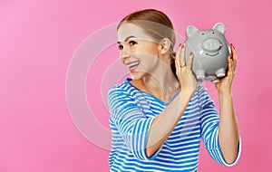 Happy woman with piggy money bank on pink background. financial planning concept