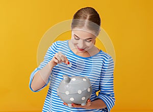 Happy woman with piggy money bank on pink background. financial planning concept