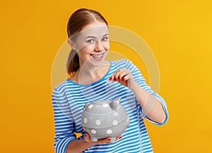 Happy woman with piggy money bank on yellow background. financial planning concept