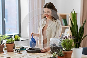 happy woman planting pot flowers at home